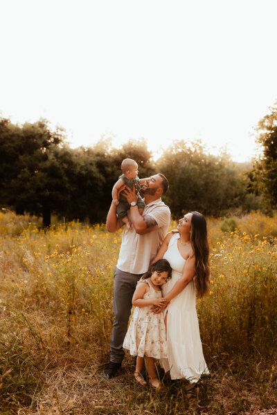 A family of four walking through a stunning wildflower field at golden hour. 