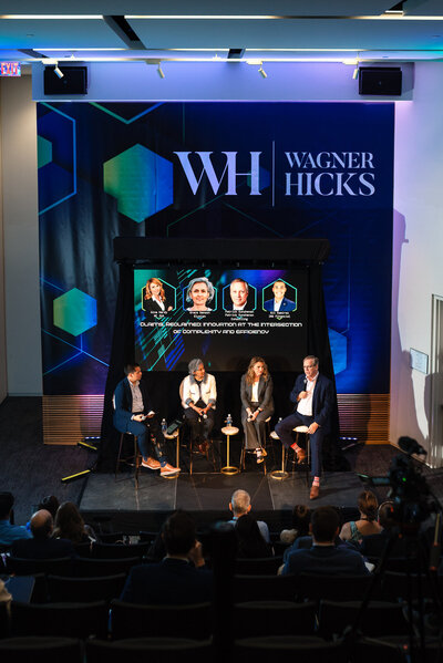 Wide-angle photo of a professional panel discussion during a corporate conference at the Dubois Center in Charlotte, NC, captured by DeLong Photography, a Charlotte event photographer.