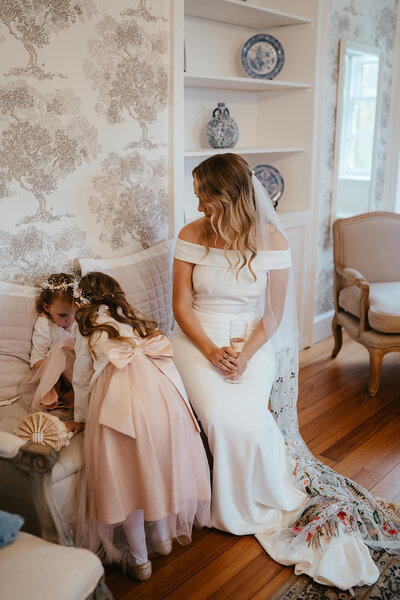 Bride seated watching her flower girls play at Wedderlie House