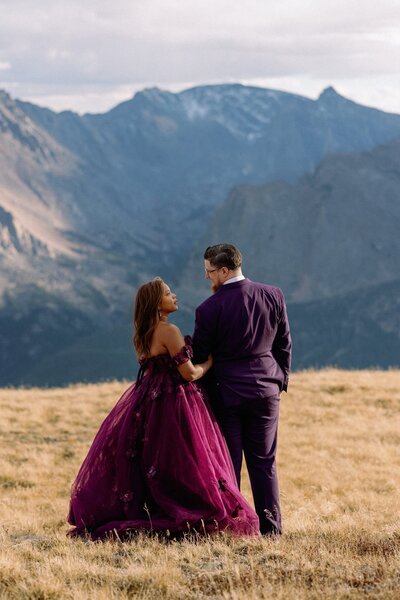 Bride in purple dress embraces groom during mountain elopement.