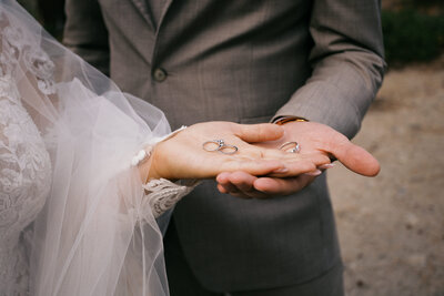 Western bridal portrait of bride sitting on a beach rock holding a bouquet with waves in the background