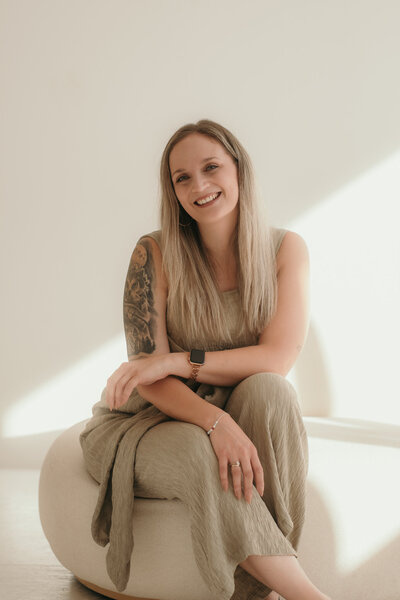 Karin Busch, Hochzeitsfotografin, sitzt lächelnd auf einem Sitzsacl