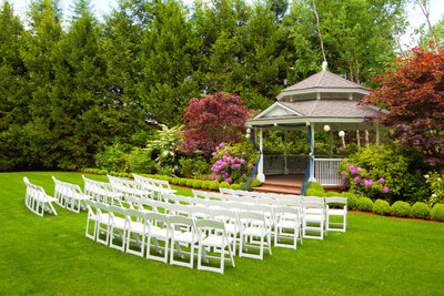 Outdoor greenery wedding with white chairs for guests
