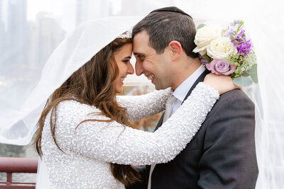 Young Jewish Couple in Chicago getting Married with their foreheads touching and they both are smiling