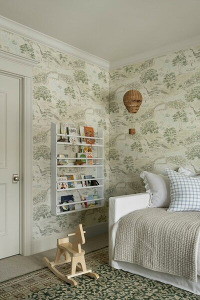 A cozy bedroom featuring patterned wallpaper and a charming rocking horse in the corner, creating a whimsical atmosphere.