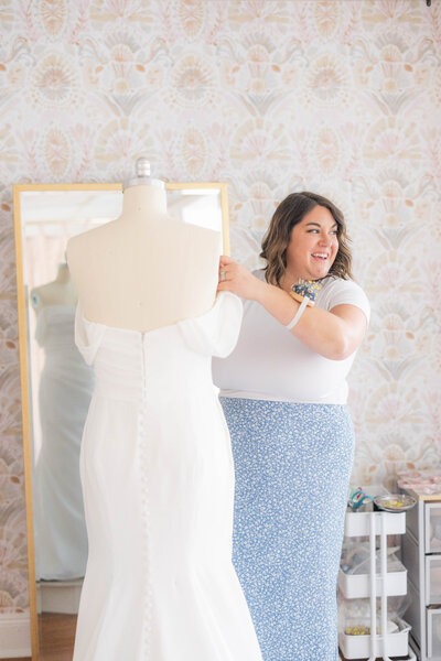 Kirstyn, the owner of Bridal Alterations by Kirstyn on Long Island sitting in front of her laptop smiling