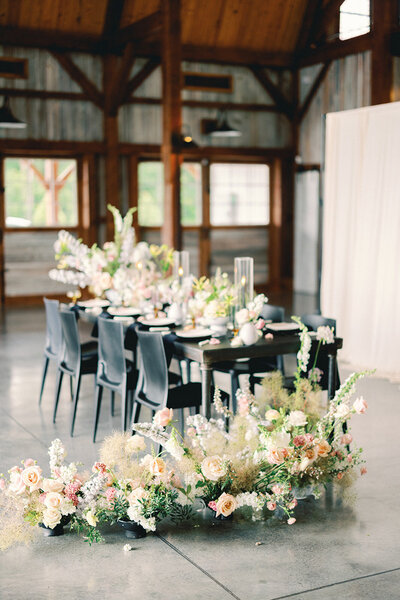 Table decorated with large floral centerpieces and other large floral arrangements on the floor