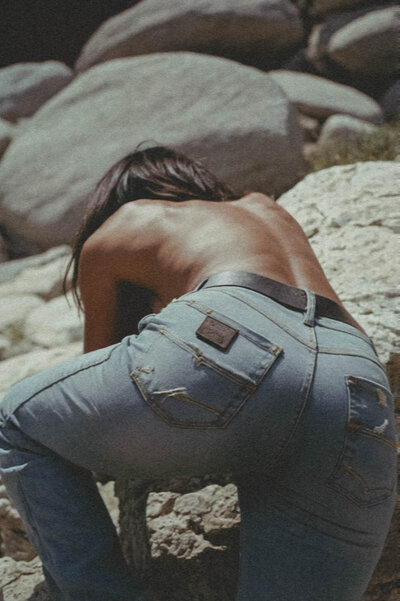 Editorial-style photo of woman in denim climbing rocks, symbolizing bold personal branding and creative direction for lifestyle businesses