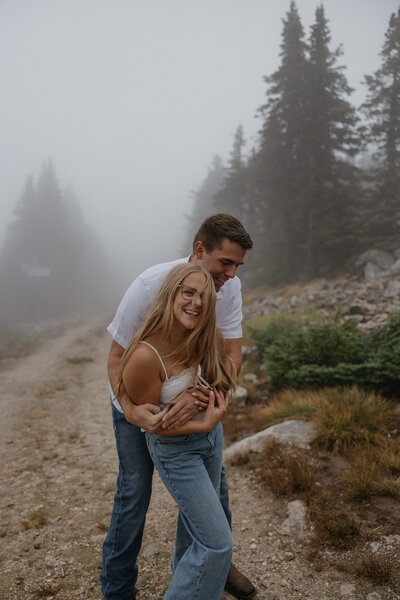 A person hugging their partner from behind as they laugh 