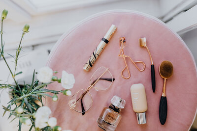 kaboompics_Makeup brushes, eyelash curler & a bottle of perfume on pink velvet