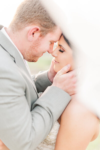 fine art joyful portrait of bride and groom coming close for a kiss while the veil sweeps over the brides shoulder in kauai by Colorado wedding photographer kari joy photography