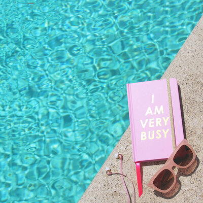 Notebook glasses and earphones by the pool