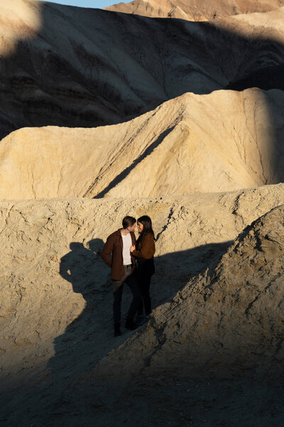 A couple standing in a rocky area about to kiss