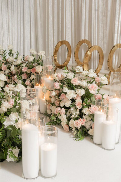 Close-up of white candles and pink floral aisle decor with gold chairs