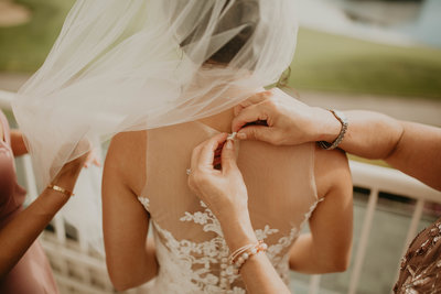Bridesmaid buttons up the back of bride's wedding gown