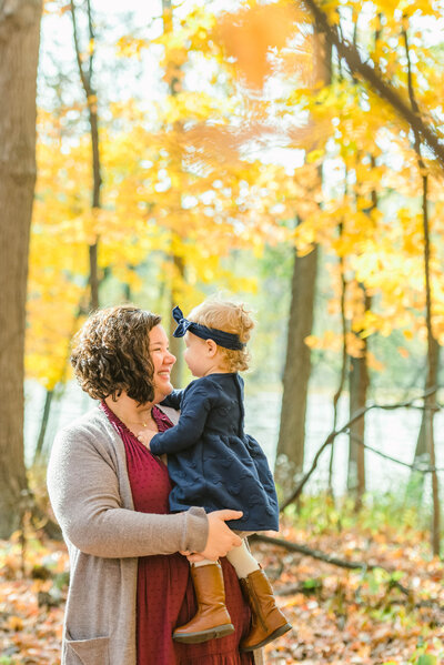 Mom playing with her toddler daughter in the fall woods by Chicago family photographer Kristen Hazelton