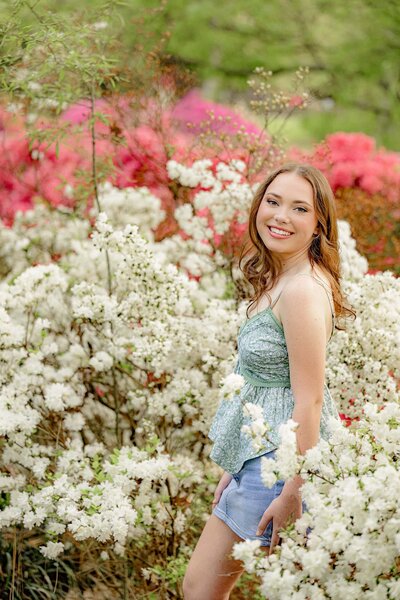cuthbertson high school graduate stands in a green floral shirt and jean shirt surrounded by flowers in a rock hill sc garden