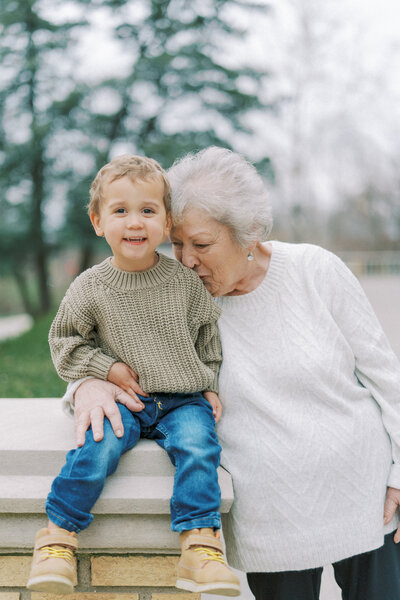 a grandma kissing her young grandson on the shoulder