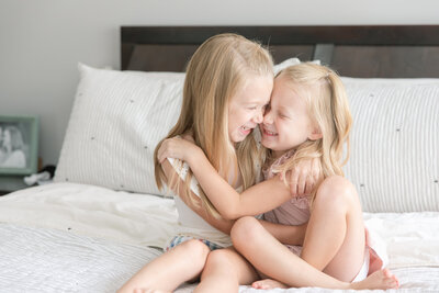 young sisters hugging on parents bed