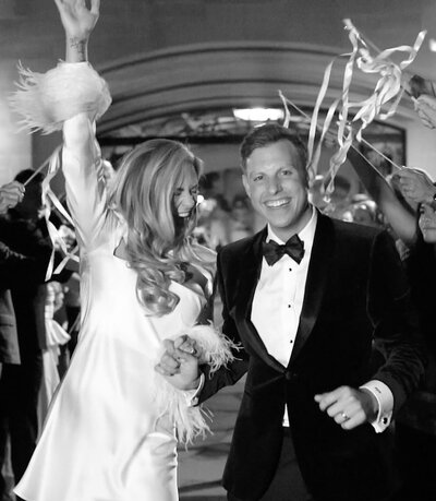 A black and white photo of a bride and groom smiling joyfully at their black-tie wedding in Beverly Hills, capturing the elegance and timelessness of the celebration.