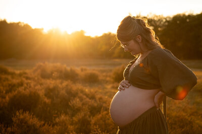 foto van zwanger mama met bolle buik op de heide in een groen tweedelig setje uit de client closet gefotografeerd door Digidroom in Malle