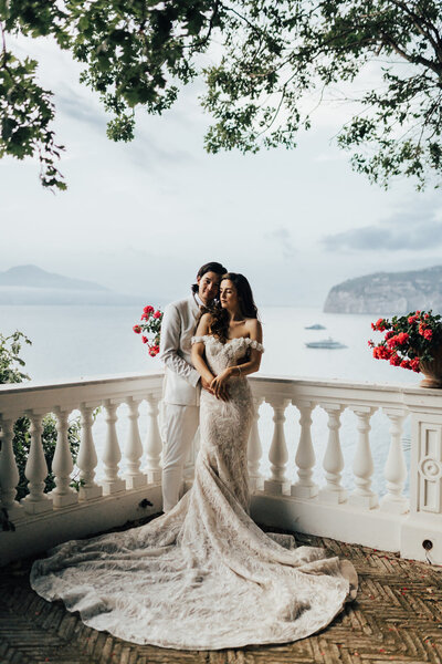 couple standing in sorrento bay on their wedding day. Bride wearing white fishtail wedding dress, groom wearing white suit