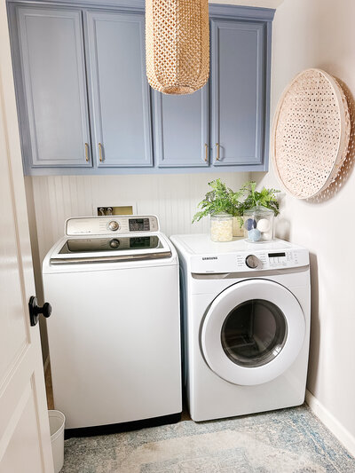 a bright laundry room with light blue cabinets and a white washer and dryer set