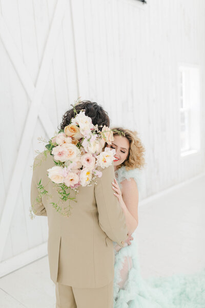 Bride and groom embracing with bouquet of flowers