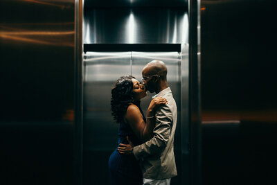 Black couple kissing in front of the elevator at ipic theater in bethesda maryland.