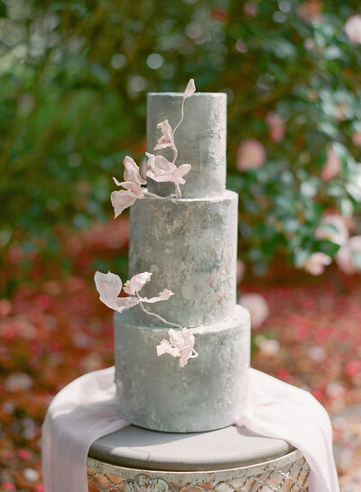 Textured gray wedding cake with three mixed size tiers and delicate pink rice paper accents