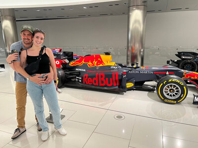 Madison and her husband, Kyle, pose next to a Red Bull Formula 1 car at the Prince of Monaco's Car Collection museum, reflecting her love for speed, travel, and bold energy.