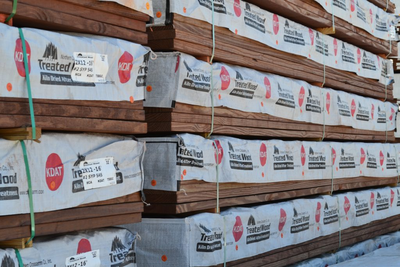 Large stacks of wrapped KDAT lumber at a warehouse yard. 