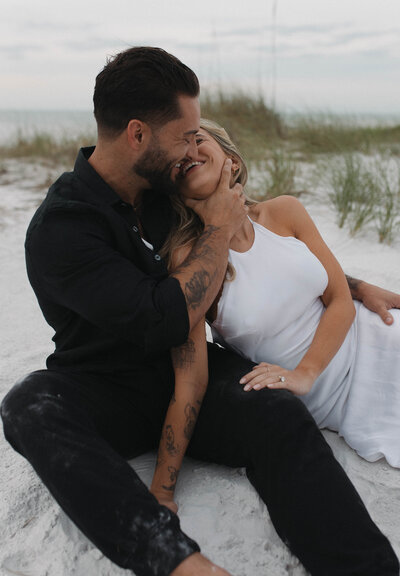 Intimate beach elopement couple laughing and embracing, candid and romantic moment for couples seeking relaxed, natural wedding photography