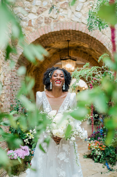 Black Bride smiling while holding her bouquet , She is being photographed by a Black Seattle Wedding Photographer.