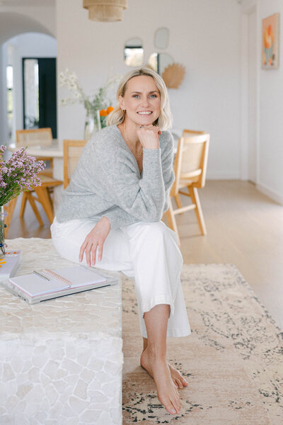 Photo of Zelda Green, entrepreneur, photographer and financial educator smiling at camera in a grey cardigan