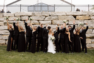 Photo of married couple kissing with their wedding party cheering