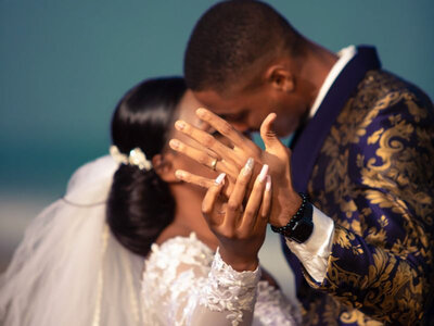 Bride and groom kissing while showing their both hands wearing wedding rings