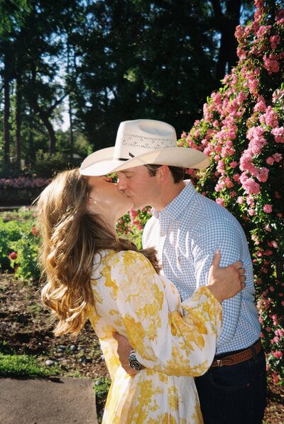 Bride and groom posing in front of wedding ceremony floral arrangement with pink flowers and green accents