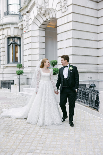 a bride and groom walking on a cobblestone street