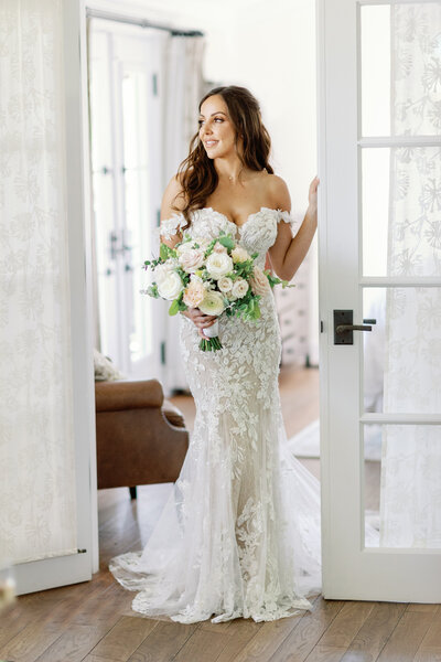 A bride holding the bottom of her dress with one hand and a bouquet of flowers with the other