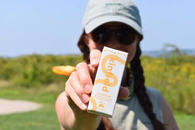 Meredith Ewenson holding a box of Kinfield sunscreen on a group hike in Rhode Island at Sachuest Wildlife Refuge in Middletown with the Rhode Island Hiking Collective