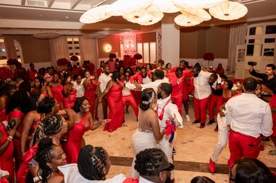 A group of people in red dresses dancing at a wedding.
