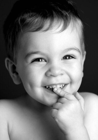 A black and white photo of a young boy with a big smile, radiating joy and innocence.