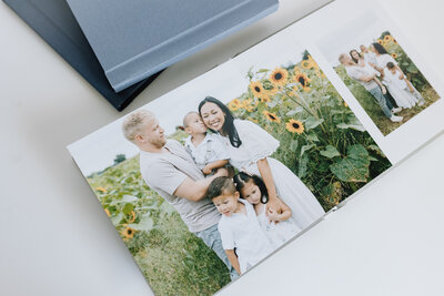 A photo print of an engaged couple smiling at each other lies on a white backdrop, with various frame corner samples lying around the print
