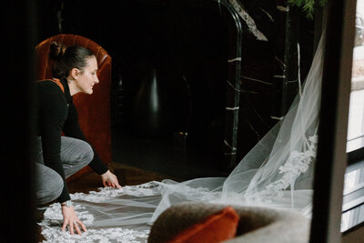 A wedding photographer leaning down and adjusting a wedding dress train 