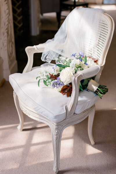 Bridal bouquet and veil on a chair in the sunlight at Great Marsh Estate in Bealeton, Virginia.