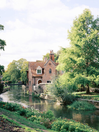 A red brick building next to a river in Canterbury, England by Katie Stansfield Photography.