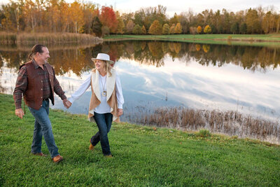 Older couple holds hands while walking by lake