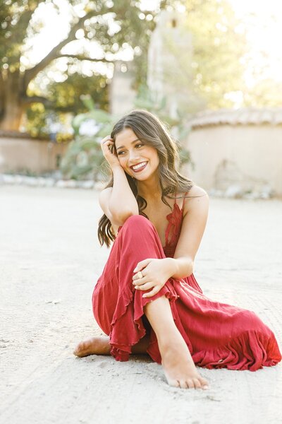 Senior portraits of a stylish teen girl in a red dress with an editorial, fashion-inspired vibe captured in the California desert