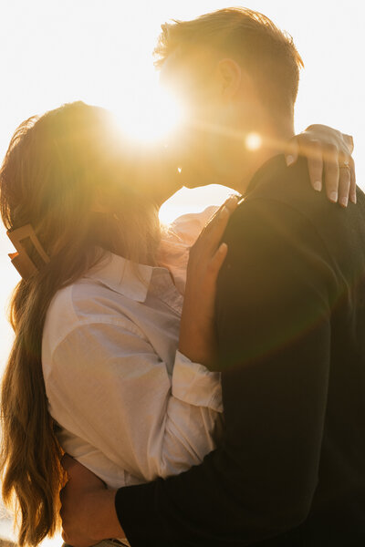 man and woman embracing and kissing with sunlight shining between them